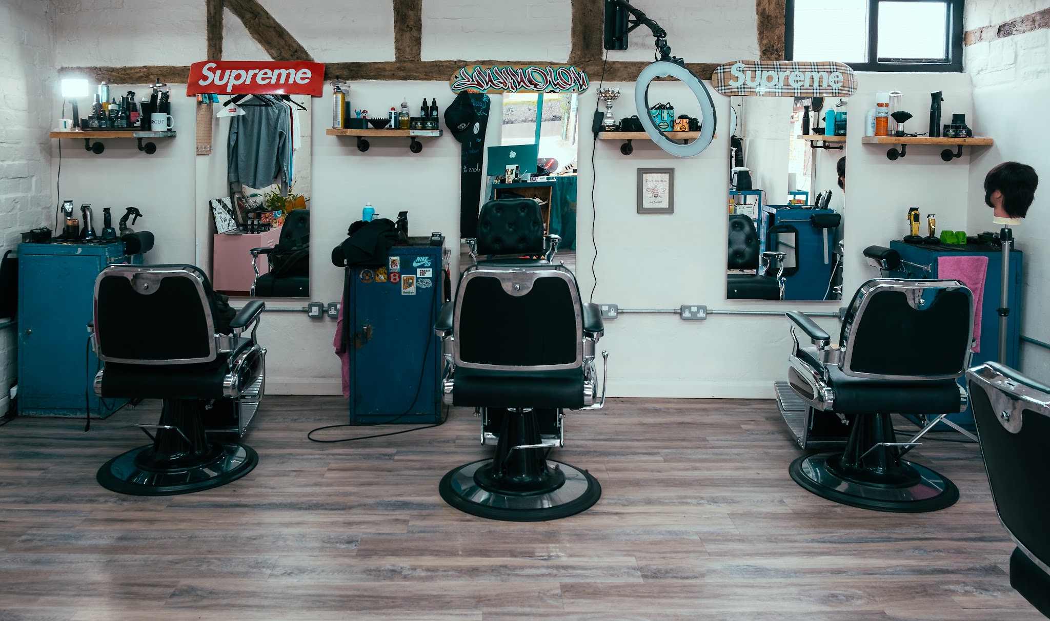 Inside the shop: three barber chairs and teal stations