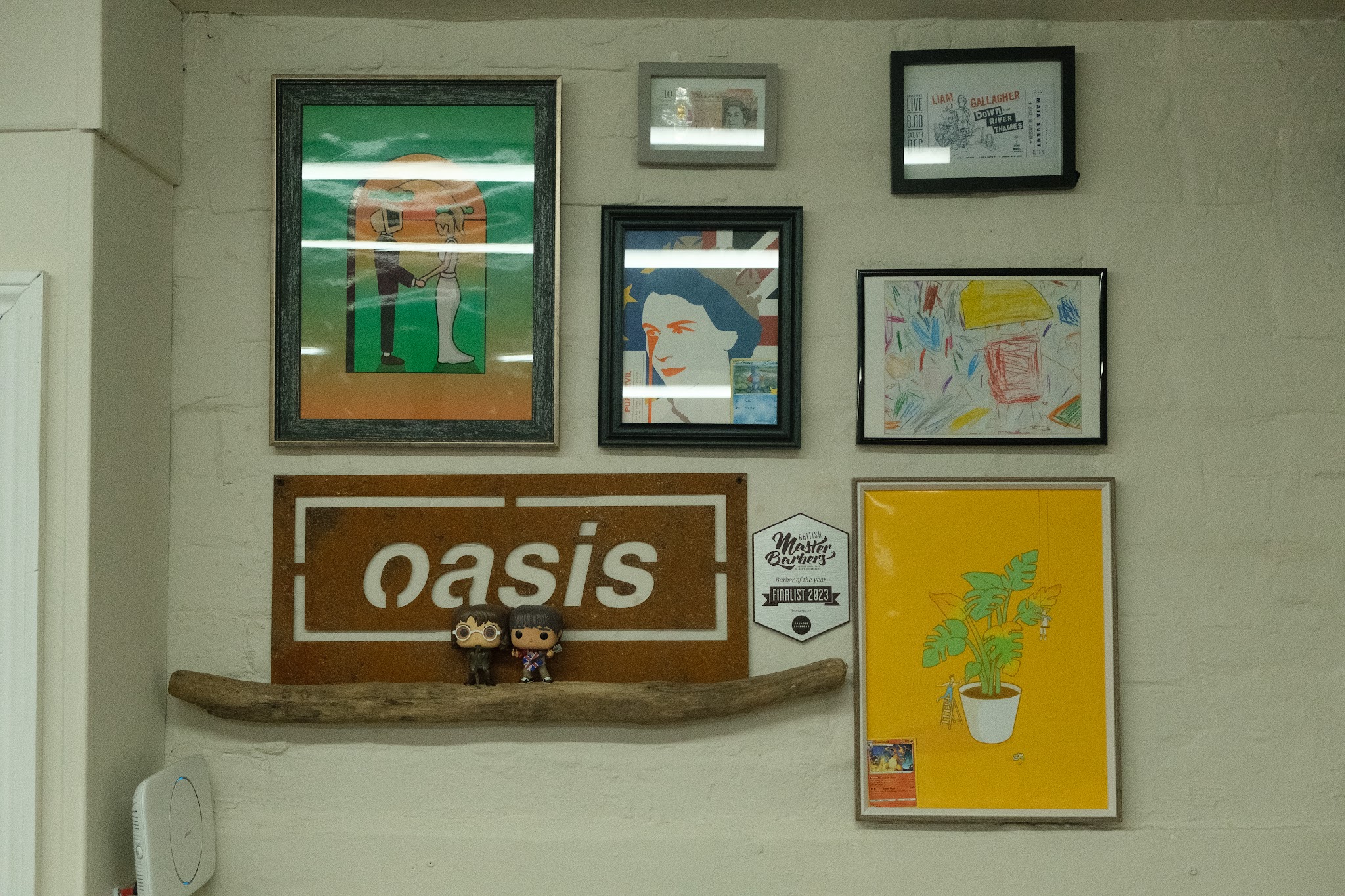 Framed art and an Oasis sign on the shop wall